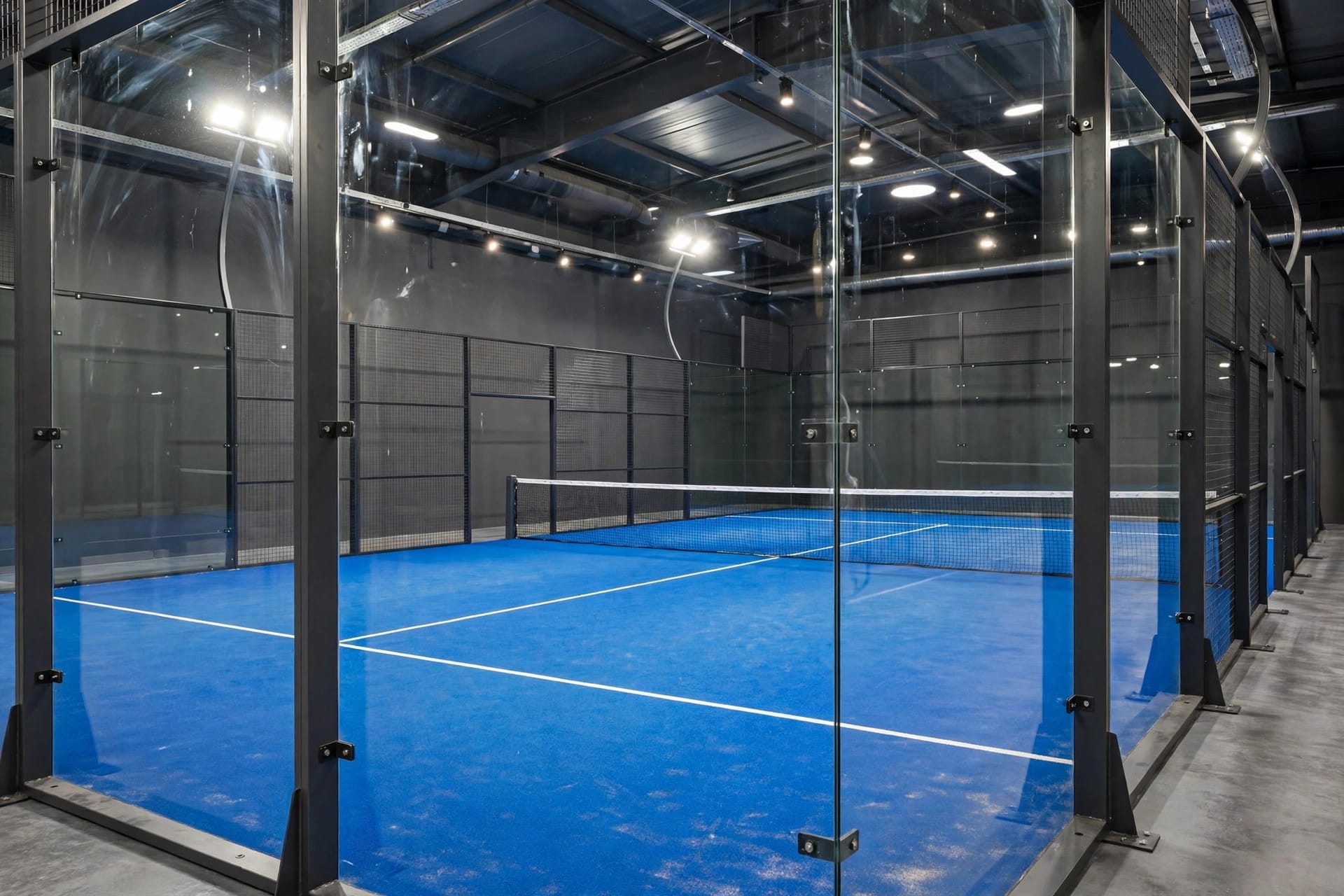 Empty blue padel court seen through glass walls