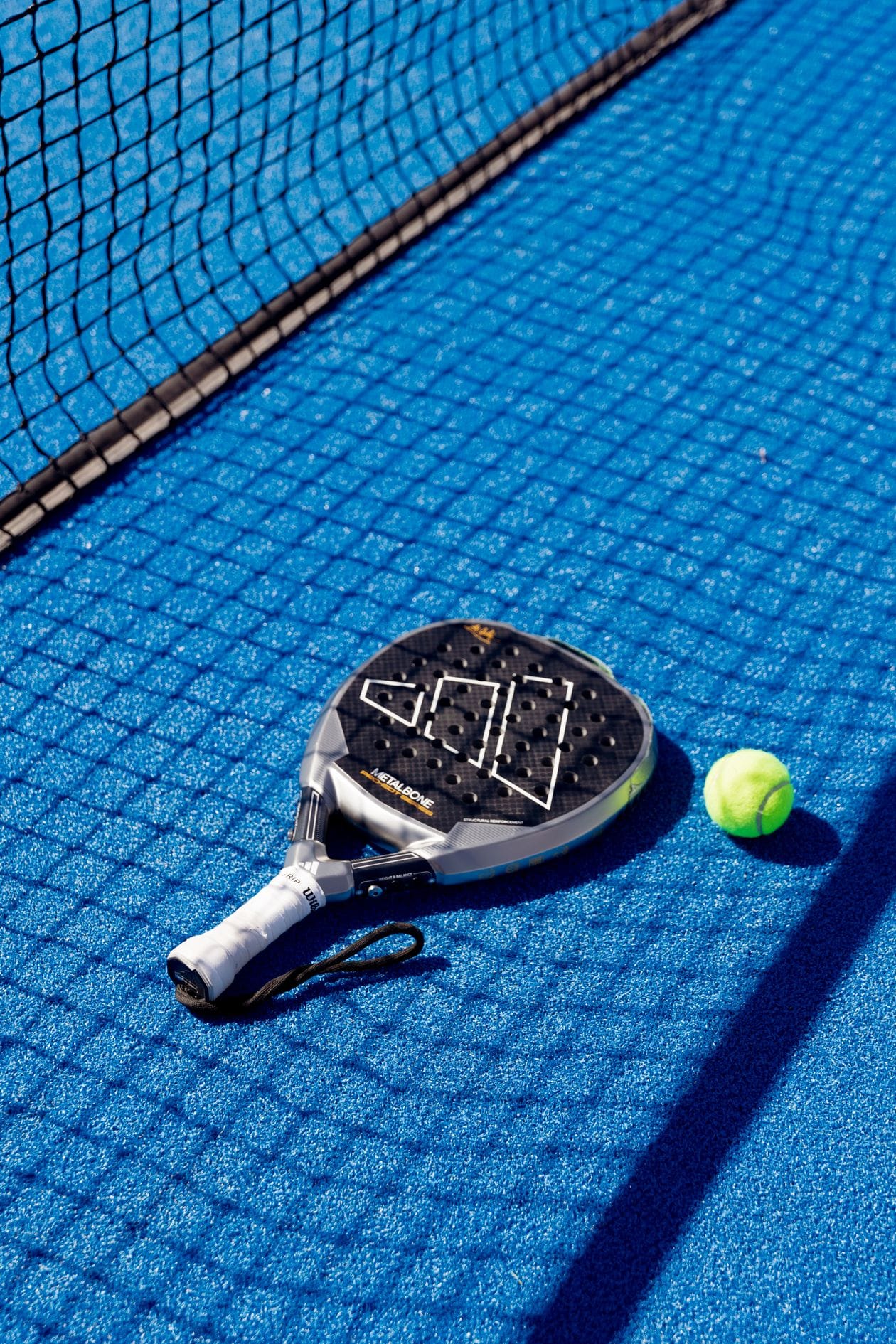 Padel racket and ball on a blue court
